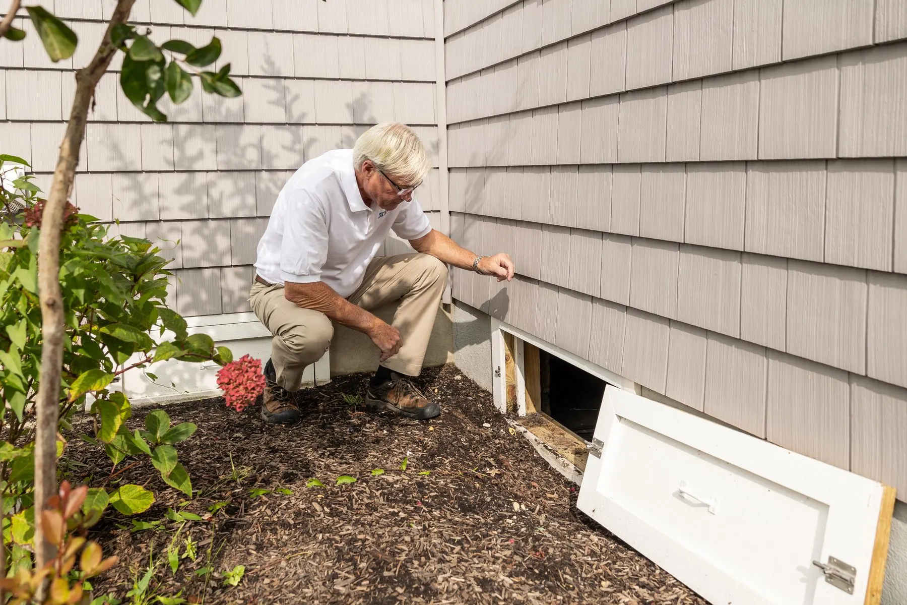 Technician checking a vent at the outside wall of a home